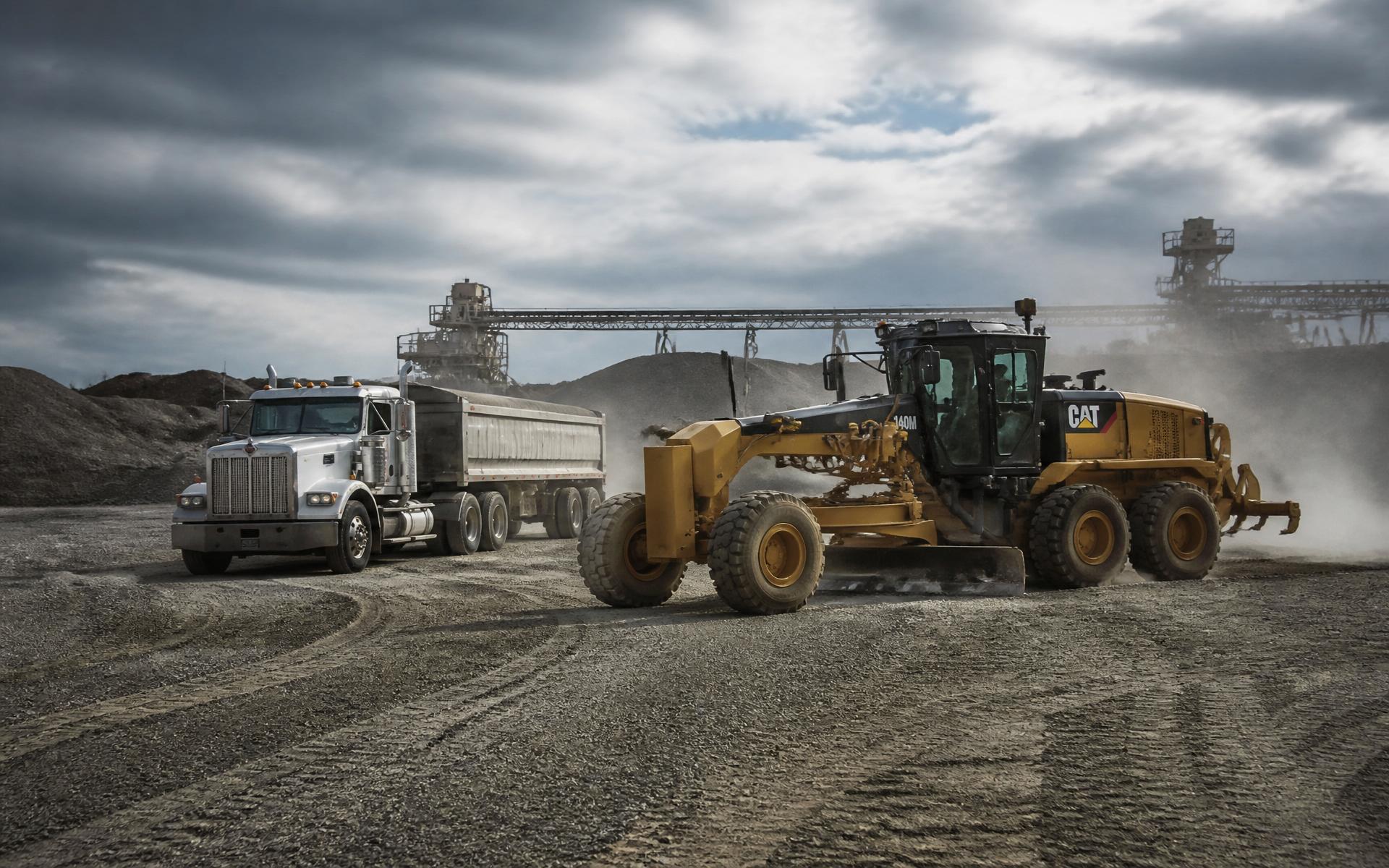 Motor grader and dump truck working on an industrial gravel yard in Houston